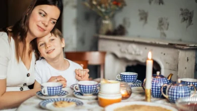 Uma mãe e seu filho compartilham um momento aconchegante em uma mesa com utensílios de café.
